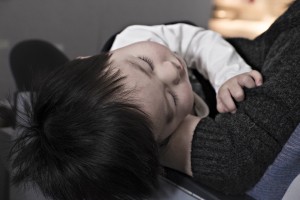 A toddler rests on someones lap.