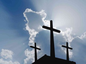 Three crosses in silhouette against a blue sky.