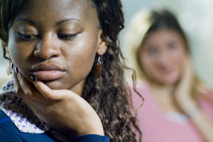 One person in the foreground is sad, while another in the background is talking