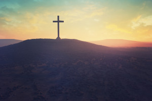 A cross silhouetted by a sunset