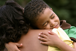 A child hugging an adult, looking happy