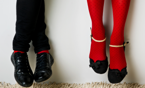 A couple sits against a wall together with their legs dangling