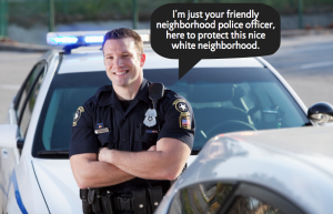 A police officer stands with their arms crossed against their chest, leaning against a cop car