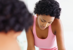 Person in a pink tank top, looking sad in the mirror