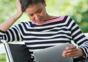 Person looking at laptop, frustrated, while sitting in wheelchair